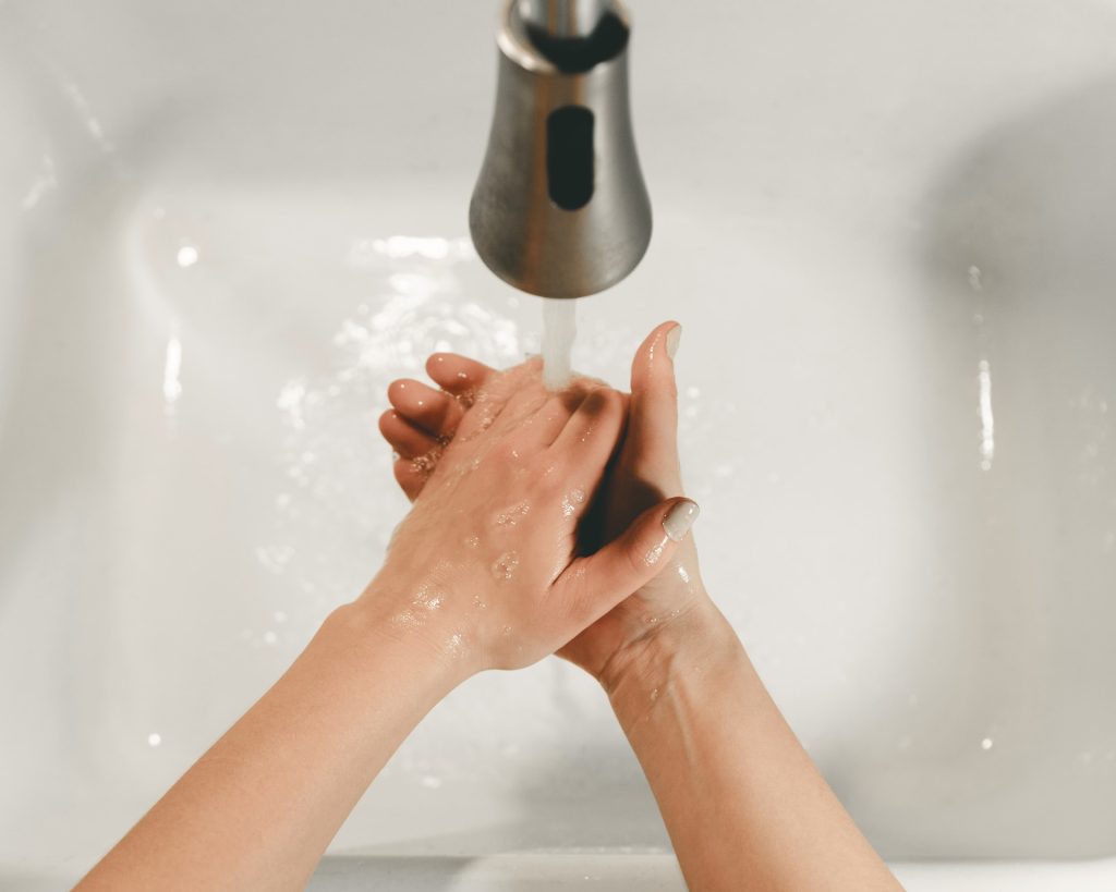 washing hands in faucet